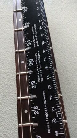 Marking the fret locations on the aluminum ruler.